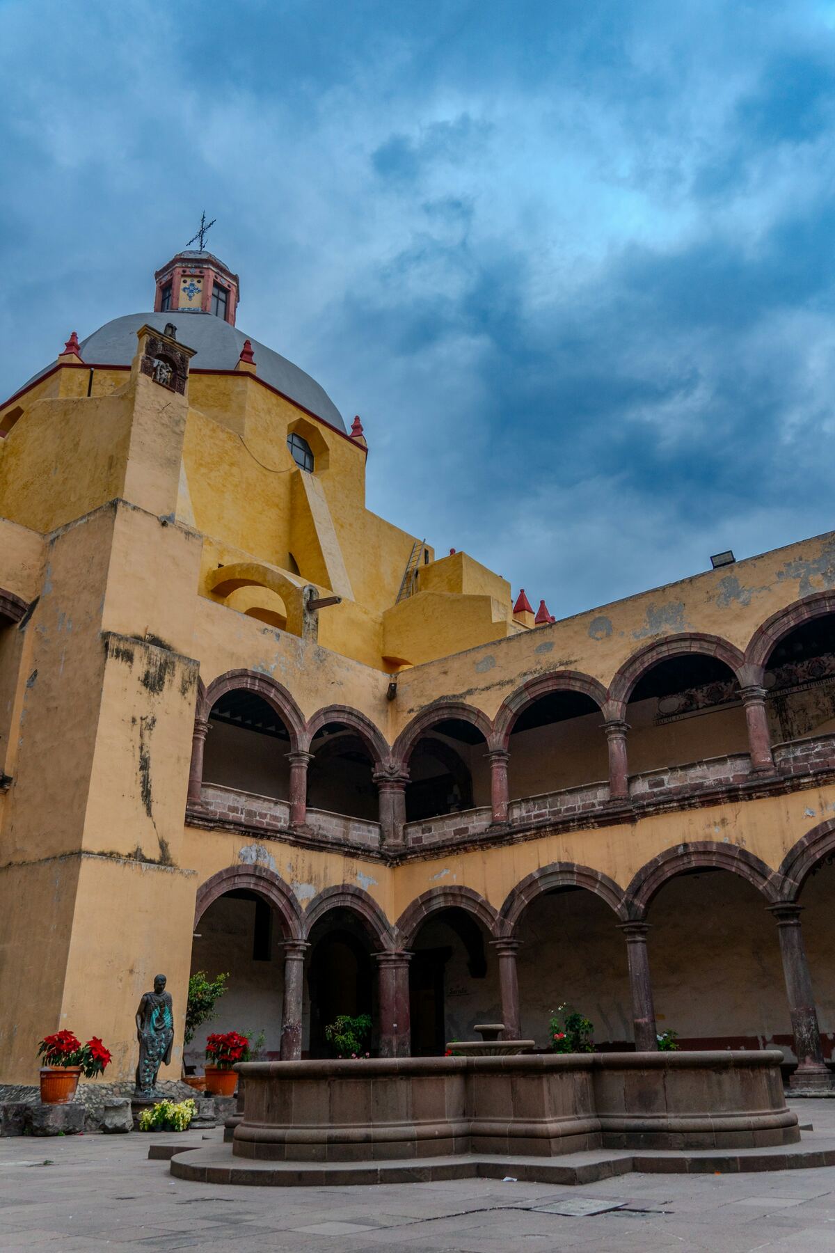 Patio de arcos amarillos con fuente de cantera al atardecer
